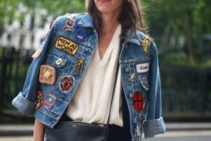 Woman with a jean jacket over her shoulders with custom patches adhered to it
