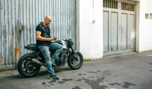 Man standing next to his motorcycle checking his phone