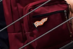 Custom flag shaped lapel pin adhered to a backpack