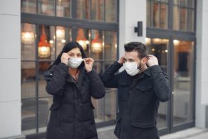 Man and women adjusting their mask while outside
