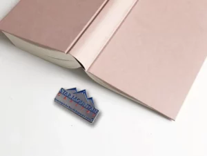 Custom corporate pin sitting next to a book