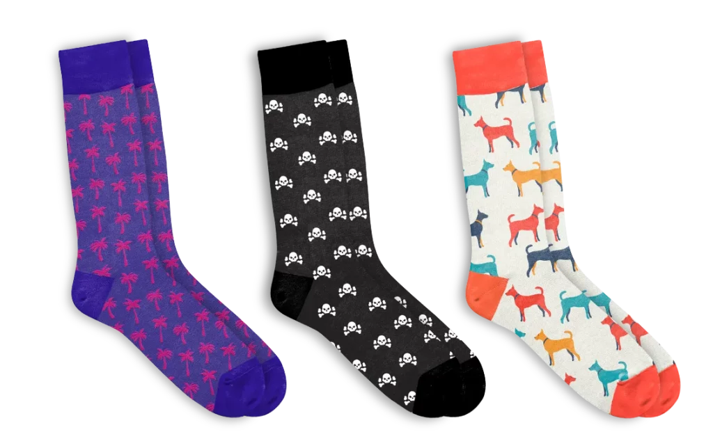 3 pairs of jacquard knit socks in purple with red palm trees, black with white skulls, and red white with dogs.