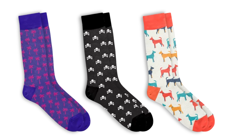 3 pairs of jacquard knit socks in purple with red palm trees, black with white skulls, and red white with dogs.